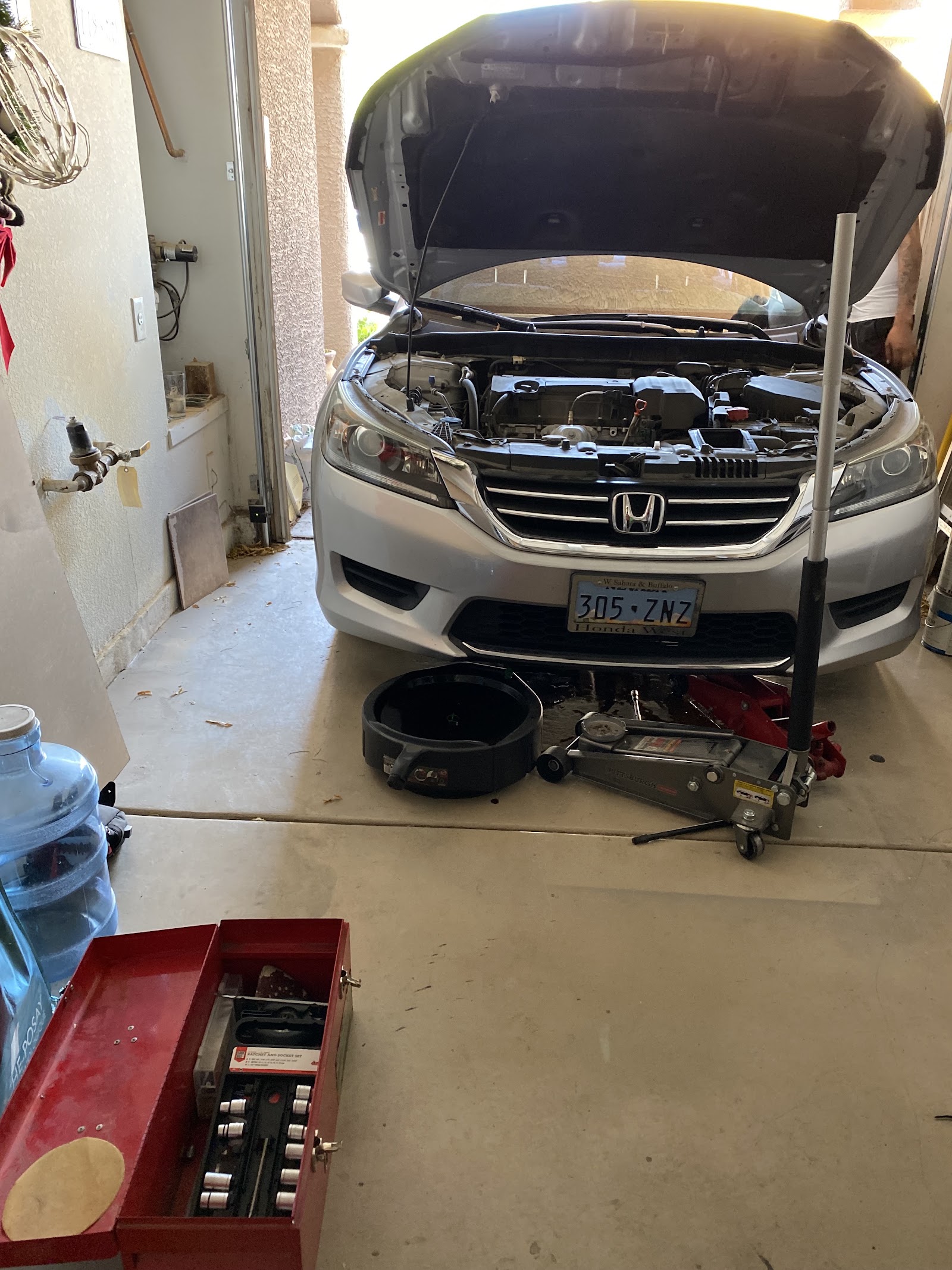 Honda Accord with hood up on a jack during an oil change in a home garage