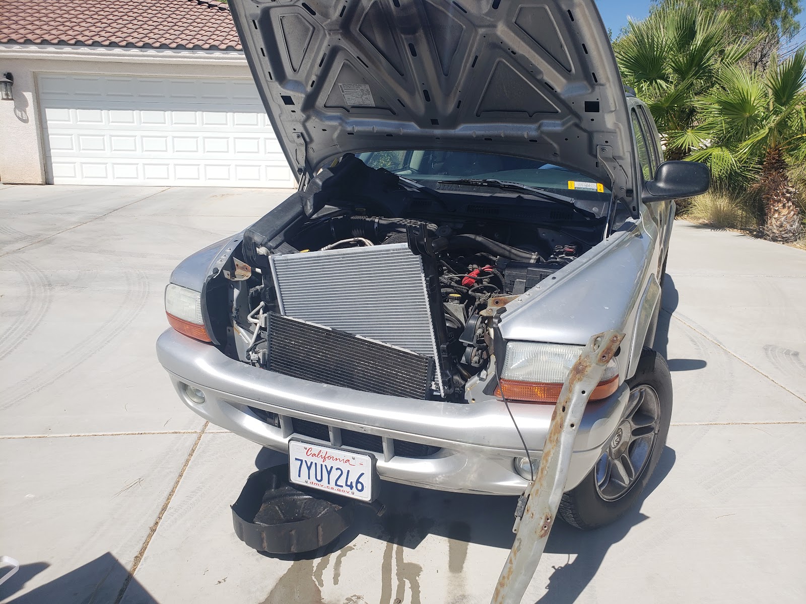 Dodge Durango with hood up and radiator and condenser pulled out for replacement in a driveway